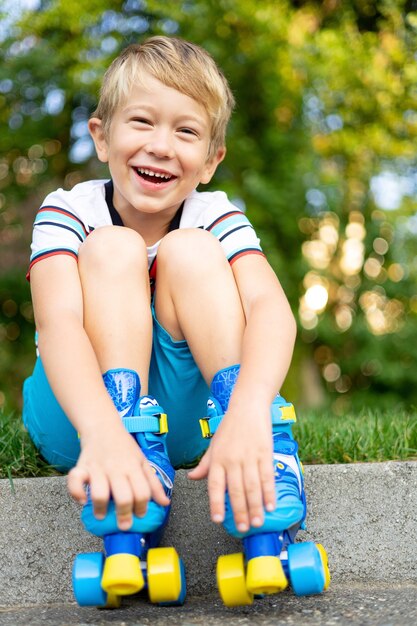 Um menino bonitinho de patins está sentado na grama o conceito de jogos ativos de esportes