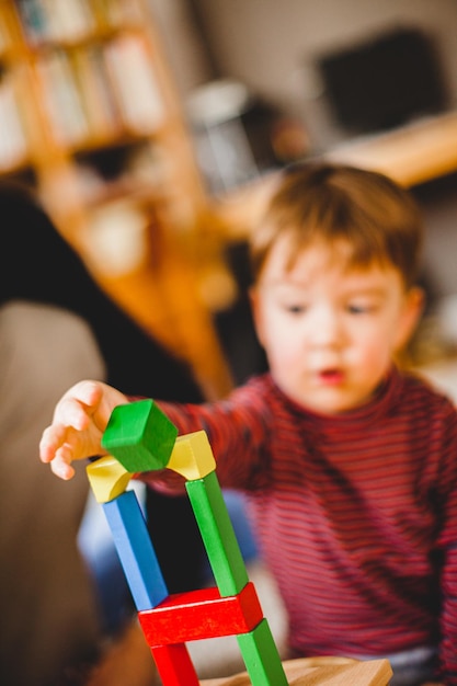 Foto um menino bonito a brincar com brinquedos em casa.