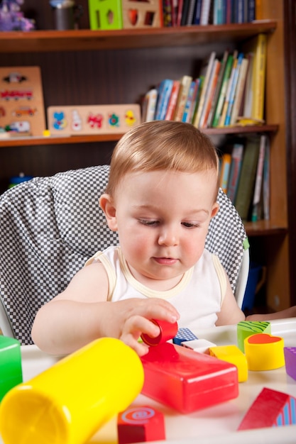 Um menino bonito a brincar com brinquedos na mesa em casa.