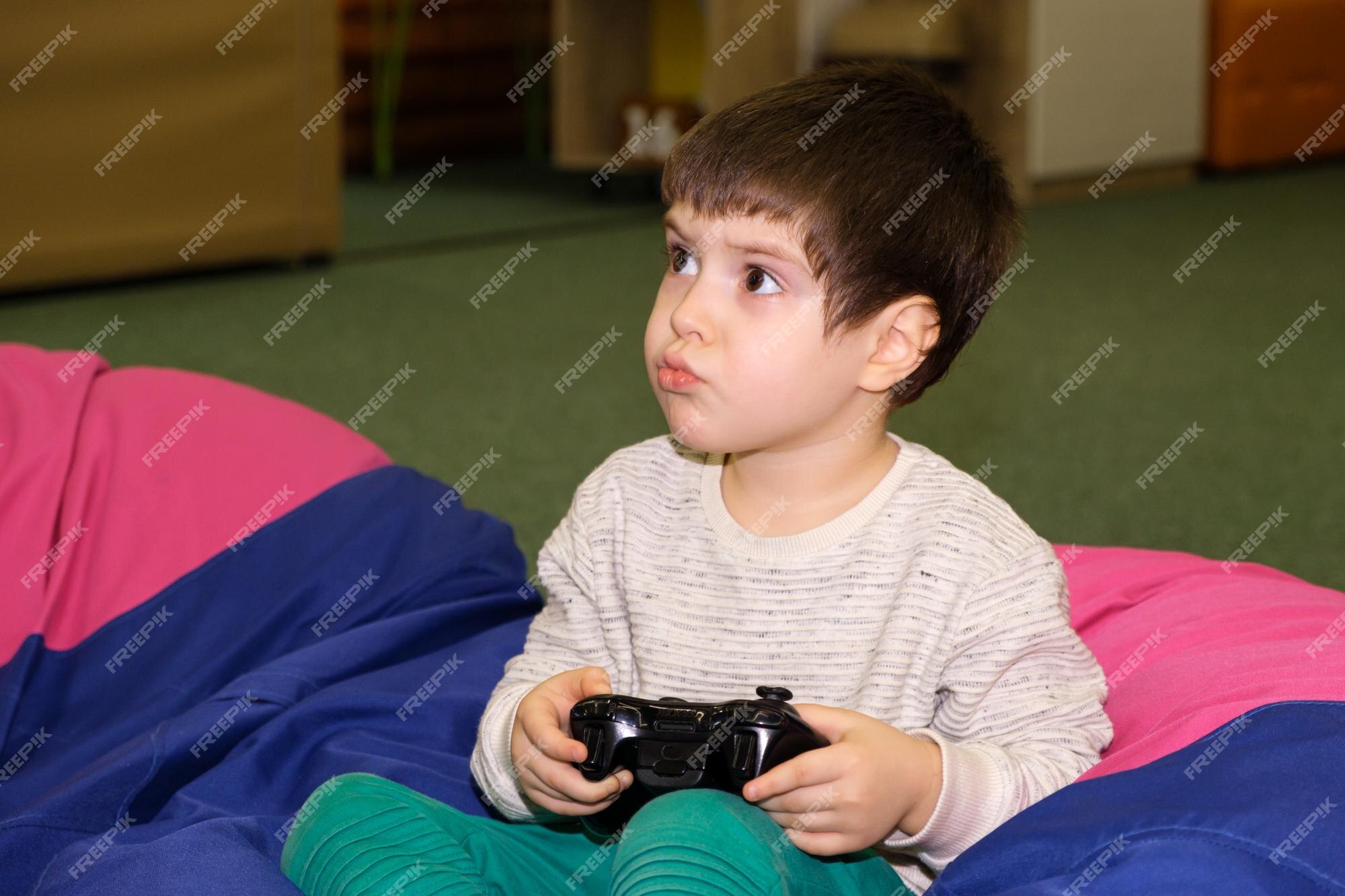 Um menino bonito de 4 anos joga um console de jogos segura um