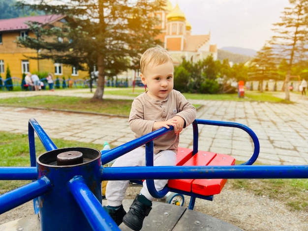 Um menino bonito de um ano e meio anda em um balanço no playground Entretenimento infantil Foco seletivo