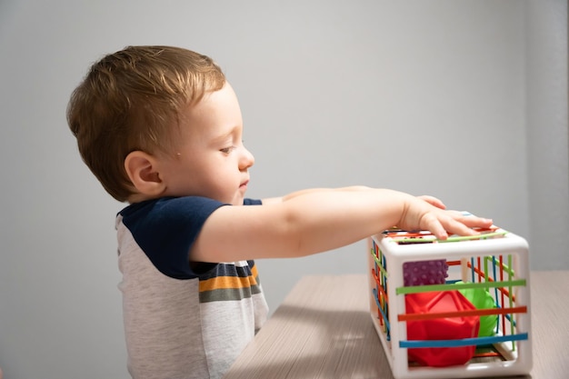 Foto um menino bonito está jogando um jogo com bolas sensoriais coloridas atividades sensoriais e táctiles
