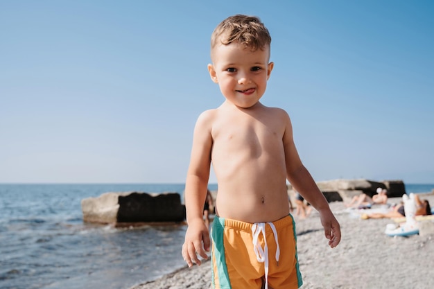 Um menino bonito está relaxando na praia Atividades ao ar livre à beira-mar