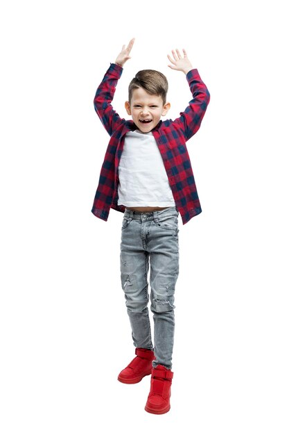 Um menino bonito gritando e rindo alegremente 56 anos de idade em jeans uma camiseta branca e uma camisa xadrez vermelha Otimismo e positividade Altura total Isolado no fundo branco Vertical