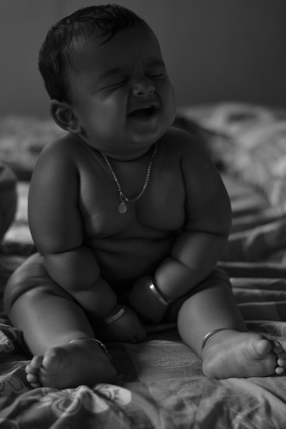 Foto um menino bonito sentado na cama.