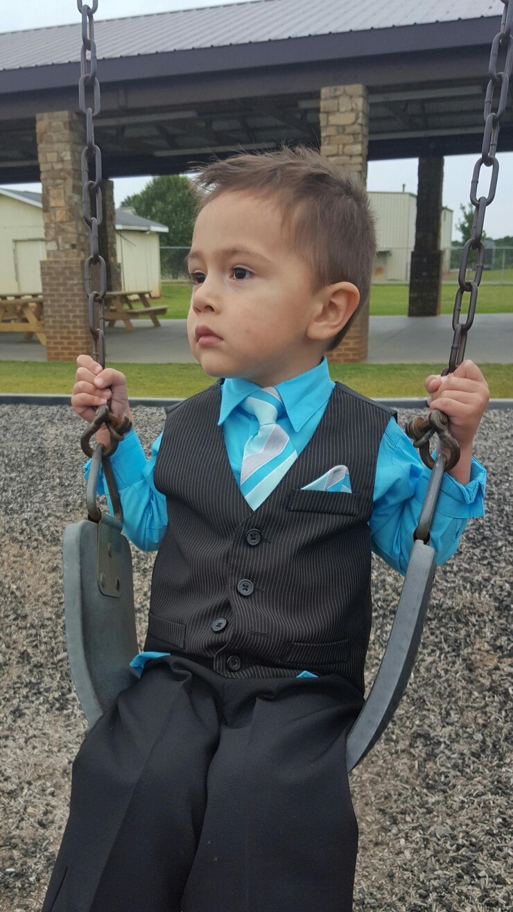 Foto um menino bonito sentado no baloiço no parque infantil.