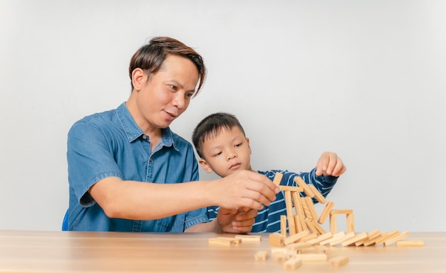 Um menino brinca com seu pai em casa com um quebra-cabeça de madeira