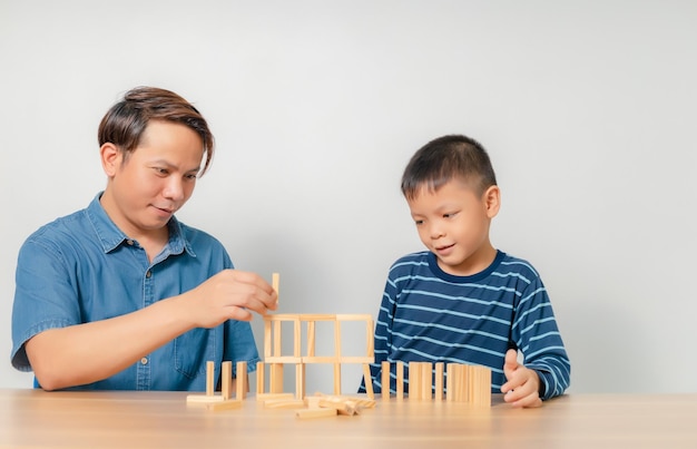 Um menino brinca com seu pai em casa com um quebra-cabeça de madeira