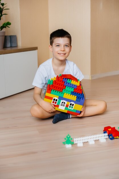 Foto um menino brinca com um kit de construção e constrói uma casa-grande para toda a família. construção de uma casa de família.
