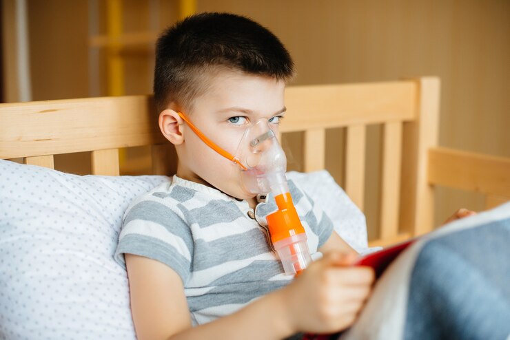 Foto um menino brinca com um tablet durante um procedimento de inalação pulmonar