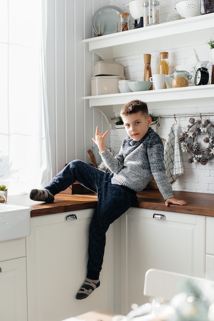 Um menino brinca na cozinha. Felicidade. Uma família.