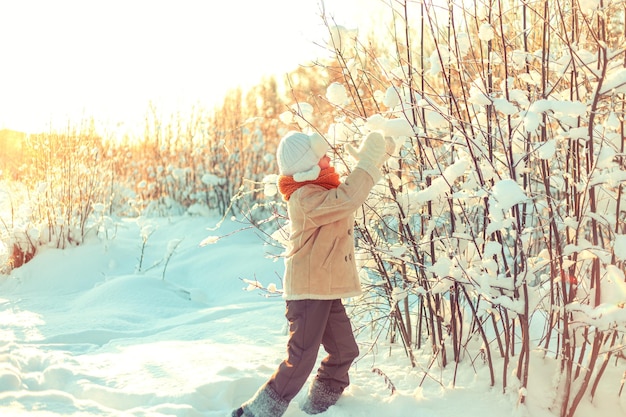 Foto um menino brinca numa floresta de inverno coberta de neve