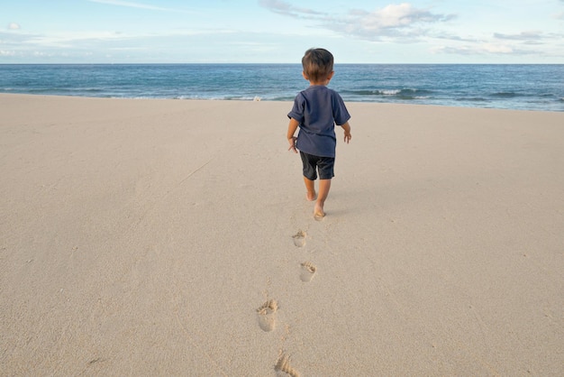 Um menino caminha na praia com a palavra praia à direita.