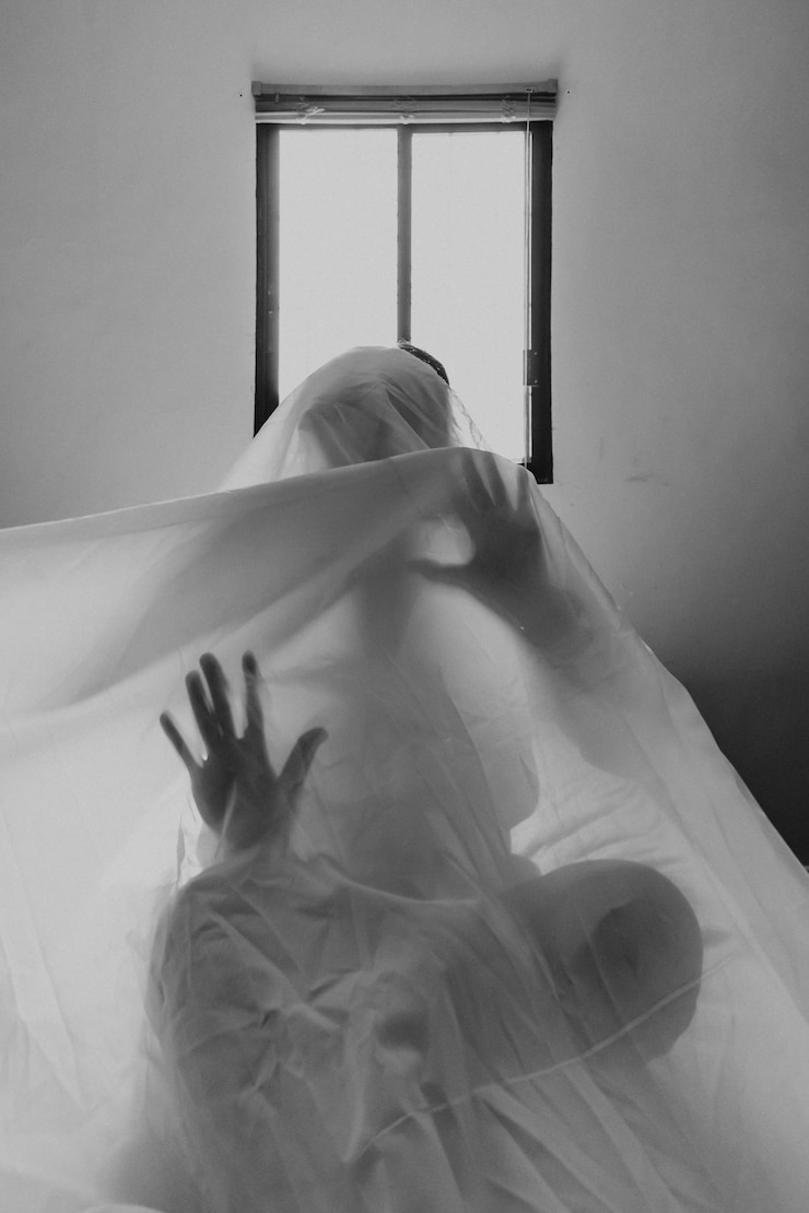 Foto um menino cantor de fantasmas debaixo de um pano com as mãos pressionadas sobre o pano