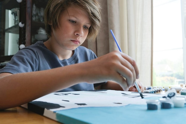 Um menino com cabelos longos e escuros desenha um quadro por números