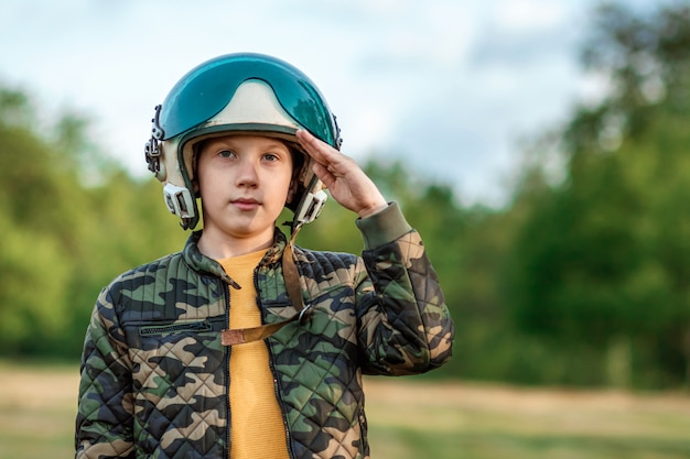 Um menino com capacete de piloto faz uma saudação.