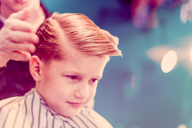 Um menino com o cabelo arrumado na barbearia