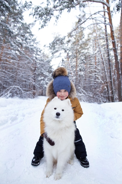 um menino com um cachorro na floresta de inverno