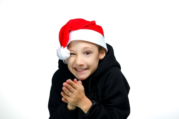 Um menino com um chapéu de Papai Noel vermelho esfrega as mãos e ri com raiva