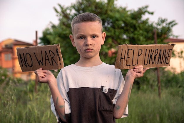 Um menino com um rosto sujo e olhos tristes segura um cartaz de papelão com a inscrição NO WAR