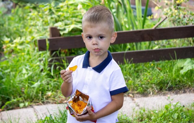 um menino come batatas fritas no parque Foco seletivo Natureza