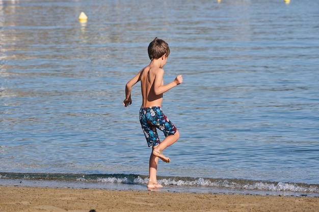 Um menino correndo na água na praia.