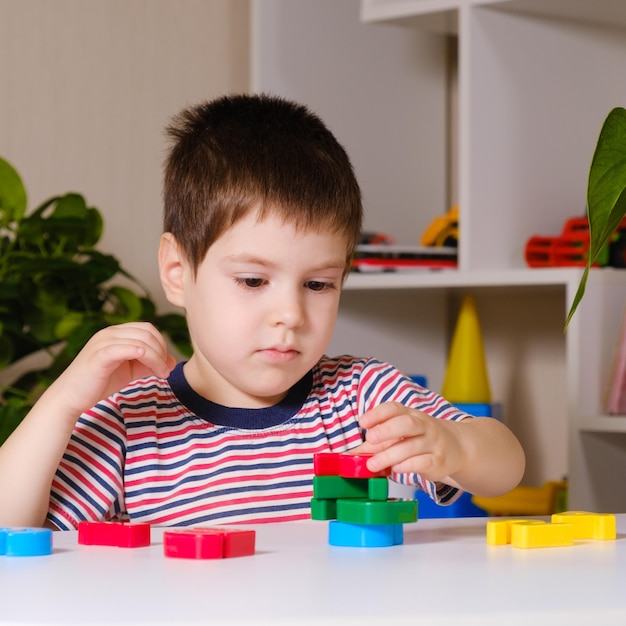 Um menino de 4 anos brinca com números multicoloridos constrói uma torre