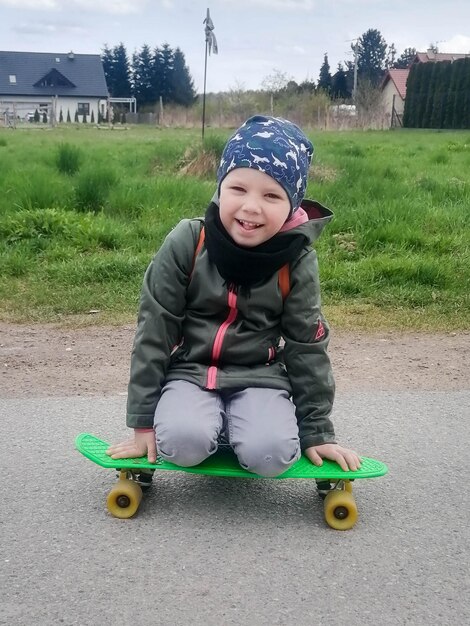 Um menino de 4 anos está a andar de camisola num mini skate.