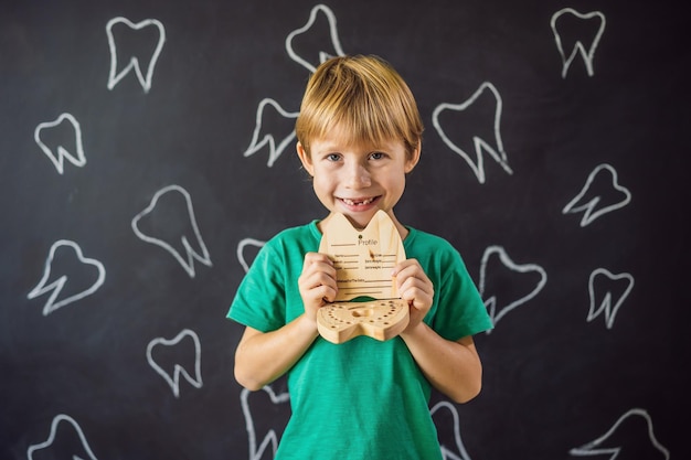 Um menino de 6 anos segura uma caixa para dentes de leite Mudança de dentes