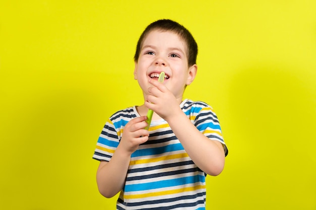 Um menino de anos segura uma escova de dentes em um fundo amarelo