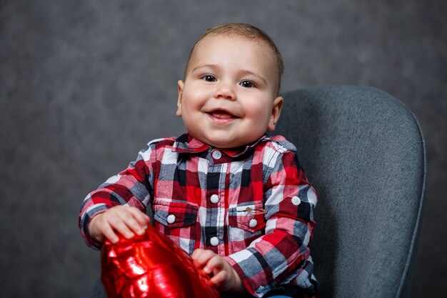 Um menino de camisa brinca com um balão em forma de coração