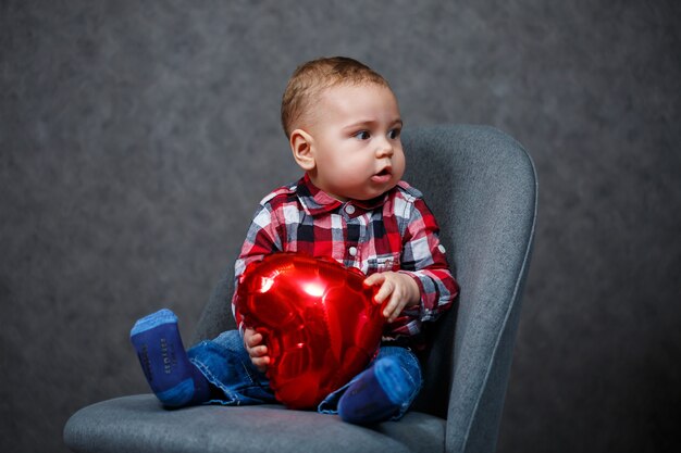 Um menino de camisa brinca com um balão em forma de coração