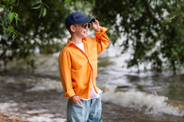 Um menino de camisa laranja à beira-mar