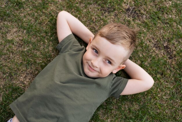 Um menino de camiseta verde encontra-se na grama verde