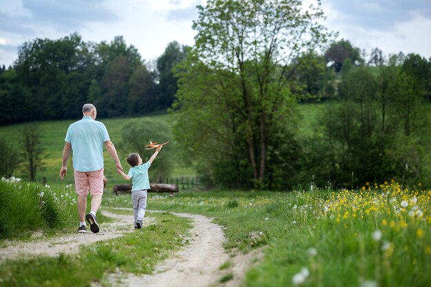 Um menino de cinco anos caminha com seu avô em uma estrada rural e eles conversam