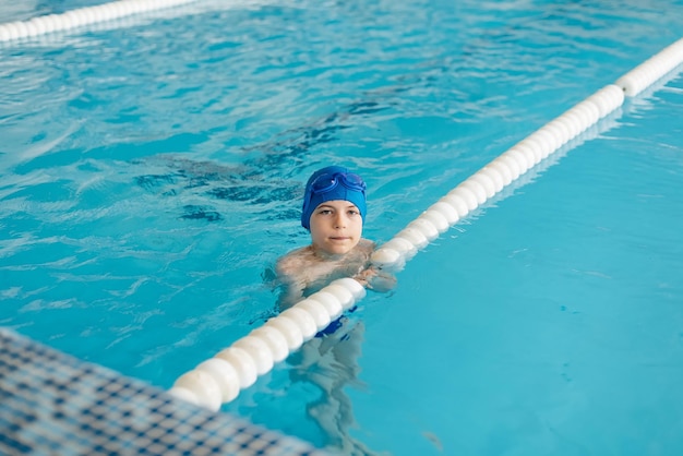 Um menino de oito anos está aprendendo a nadar em uma piscina moderna Desenvolvimento de esportes infantis Paternidade saudável e promoção de esportes infantis