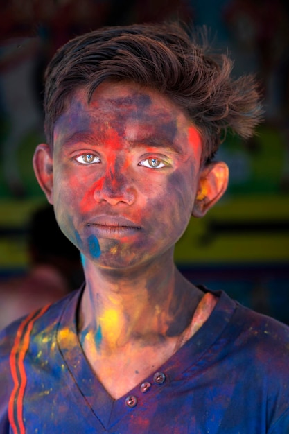 Um menino de olhos coloridos está coberto de tinta.