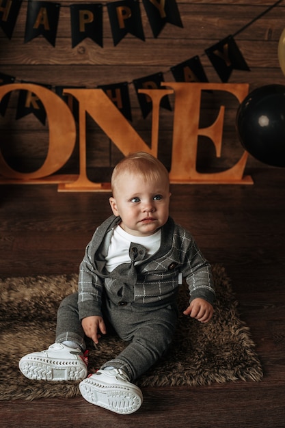 Foto um menino de terno cinza sentado em um fundo festivo
