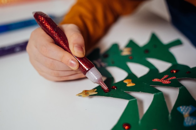 um menino decora árvores de Natal de papel para o Natal