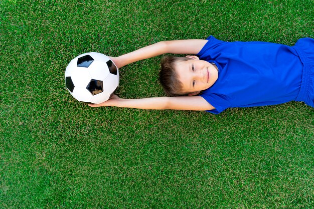 Dois jogadores de futebol masculinos deitado na grama do campo, vista  superior. jogador de futebol no estádio ao ar livre, treino antes do jogo,  treino de futebol