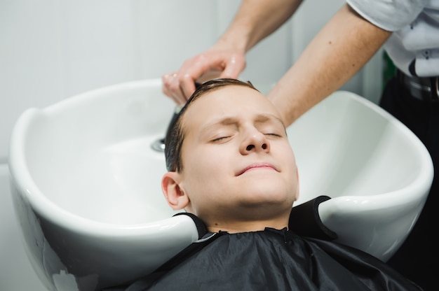 Um menino é lavado pelo cabeleireiro na barbearia