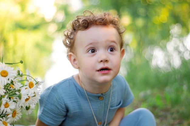 Um menino e um buquê de margaridas estão andando na natureza FOTOSESSÃO Caminhada da Felicidade Horário de verão