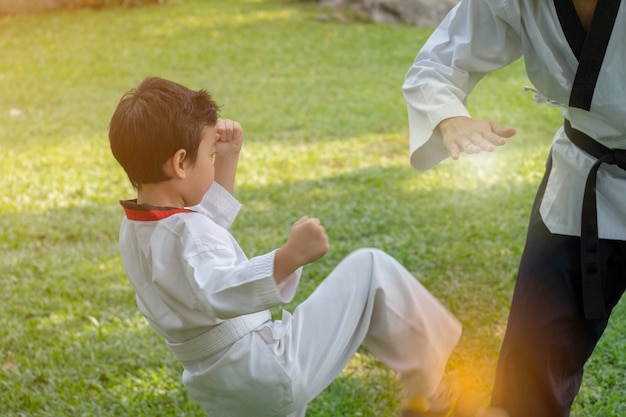 Foto um menino e um homem a praticar karatê no campo.