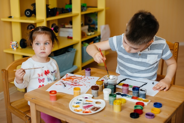 Um menino e uma menina brincam juntos e pintam. Recreação e entretenimento. Ficar em casa.