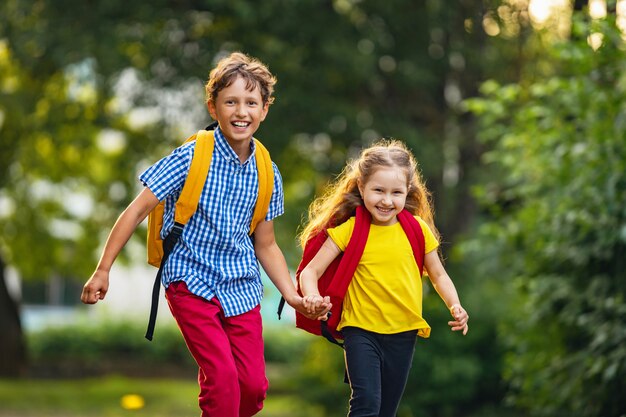 Um menino e uma menina com mochilas estão andando na rua