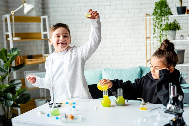 Um menino e uma menina estão fazendo um experimento químico, despejar líquido em um copo