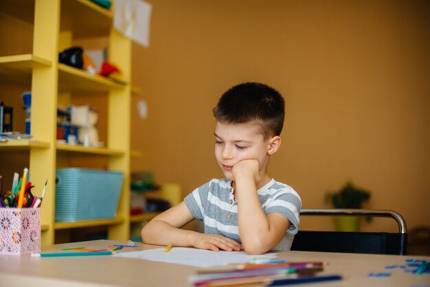 Um menino em idade escolar faz a lição de casa em casa. treinamento na escola.