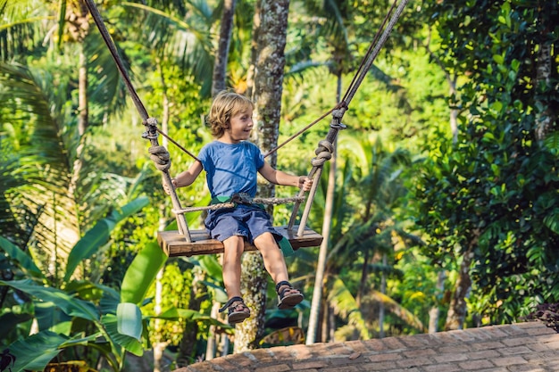 Um menino em um balanço sobre a selva, Bali.