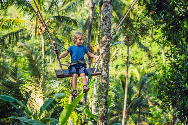 Um menino em um balanço sobre a selva, Bali.