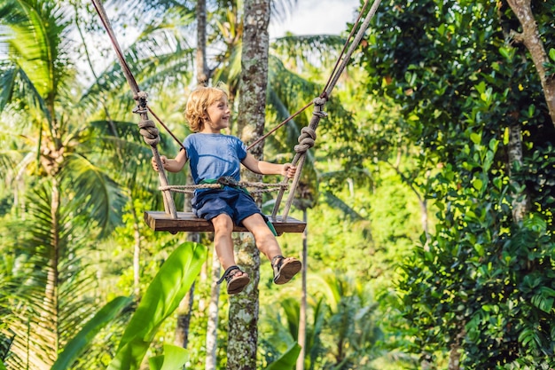 Um menino em um balanço sobre a selva, Bali.